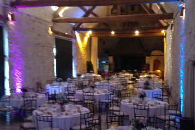 Un DJ en chemise blanche mixe de la musique sur une console lors d'un événement avec des invités en arrière-plan.