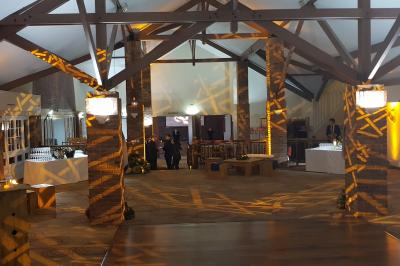 Un DJ en chemise blanche mixe de la musique sur une console lors d'un événement avec des invités en arrière-plan.