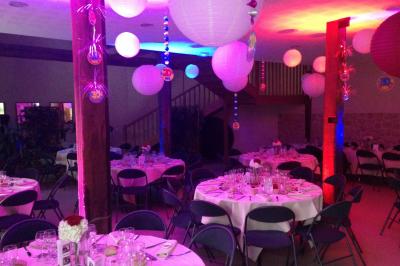 Un DJ en chemise blanche mixe de la musique sur une console lors d'un événement avec des invités en arrière-plan.