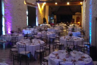 Un DJ en chemise blanche mixe de la musique sur une console lors d'un événement avec des invités en arrière-plan.