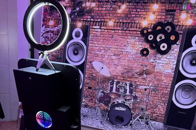 Borne photo interactive avec écran tactile et anneau lumineux, installée dans un espace intérieur avec des plantes…