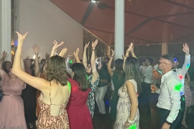 Personnes dansant sur une piste éclairée, vue depuis une table de mixage avec écran affichant des pistes audio.