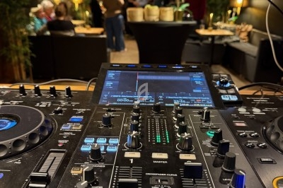 Table de mixage DJ en gros plan dans un espace intérieur animé avec des personnes en arrière-plan.