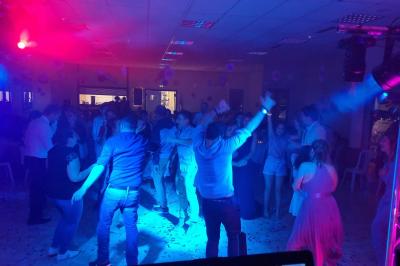 Vue depuis une scène sur une salle de réception où des invités dansent sous des lumières colorées.