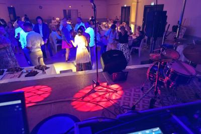 Vue depuis une scène sur une salle de réception où des invités dansent sous des lumières colorées.