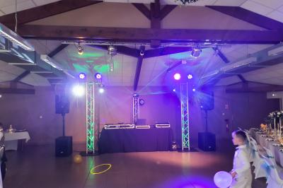 Vue depuis une scène sur une salle de réception où des invités dansent sous des lumières colorées.