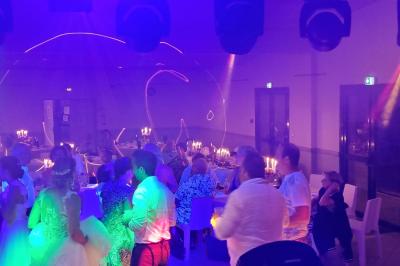 Vue depuis une scène sur une salle de réception où des invités dansent sous des lumières colorées.