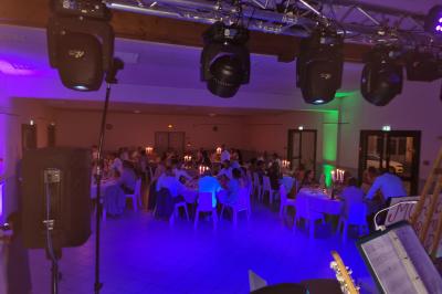 Vue depuis une scène sur une salle de réception où des invités dansent sous des lumières colorées.