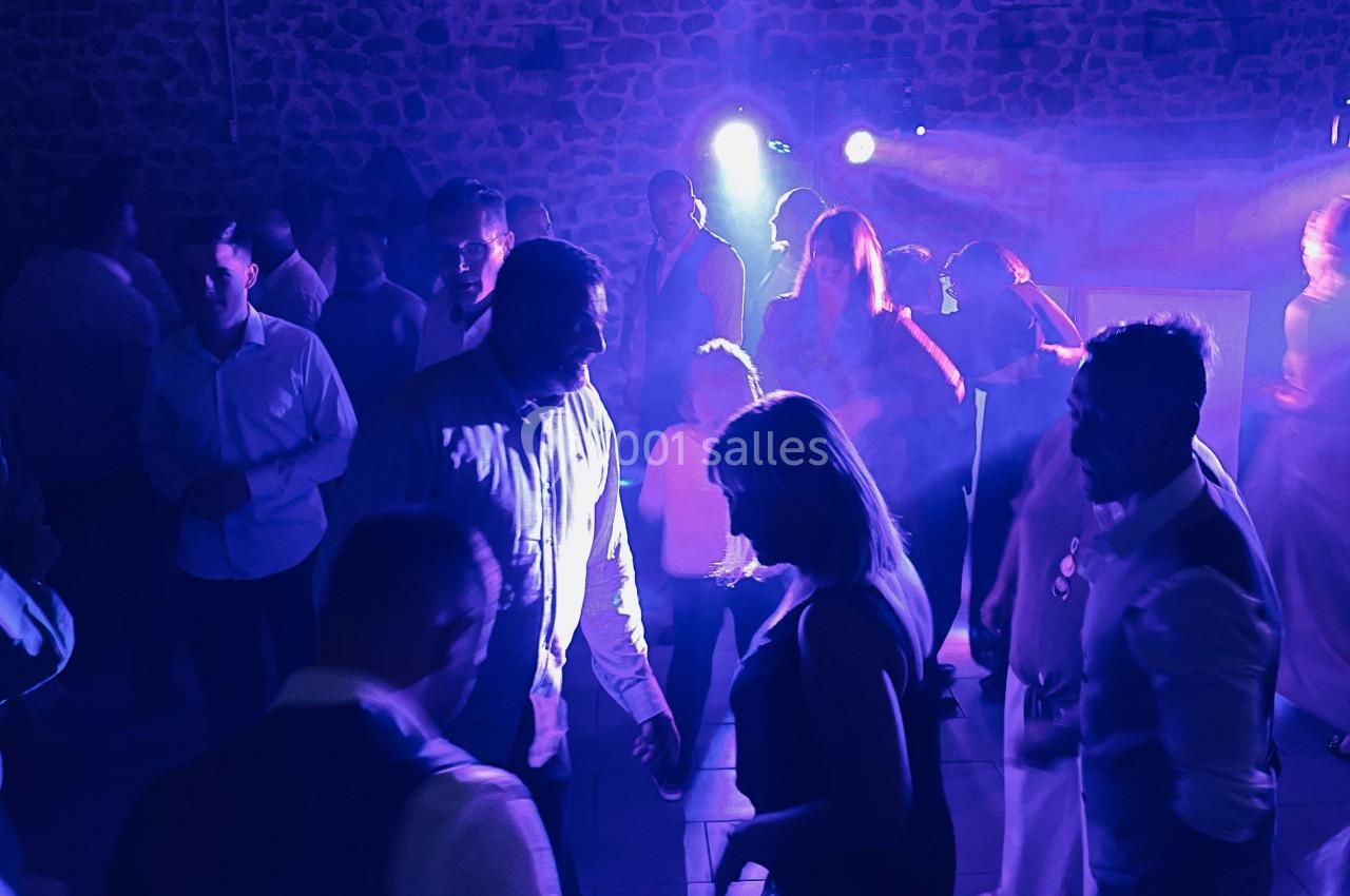 Des personnes dansent sous des lumières bleues et violettes dans une ambiance festive en intérieur.