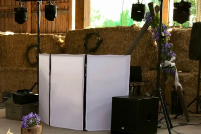 Salle de réception en pierre avec plafond en bois, tables rondes dressées et éclairage chaleureux.