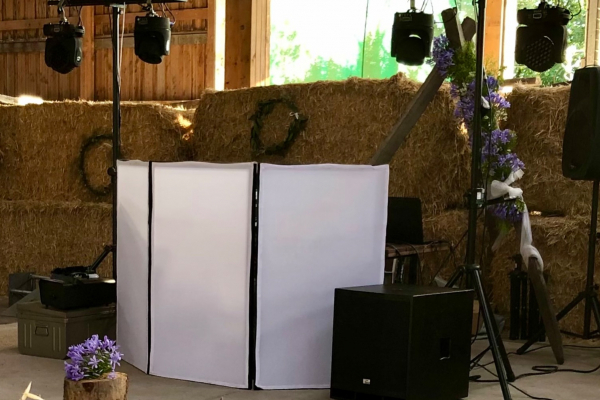 Installation de matériel de sonorisation et éclairage dans une grange décorée avec des bottes de foin et des fleurs.