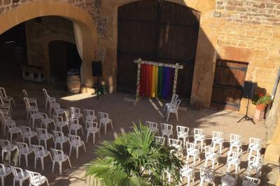 Salle de réception en pierre avec plafond en bois, tables rondes dressées et éclairage chaleureux.