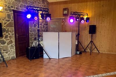 Salle de réception en pierre avec plafond en bois, tables rondes dressées et éclairage chaleureux.