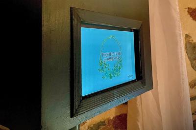 Salle de réception en pierre avec plafond en bois, tables rondes dressées et éclairage chaleureux.