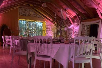 Salle de réception en pierre avec plafond en bois, tables rondes dressées et éclairage chaleureux.