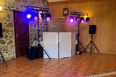 Installation de matériel de sonorisation et éclairage coloré dans une salle aux murs en pierre et bois.