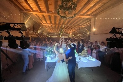 Un couple de mariés danse devant des invités dans une salle décorée de guirlandes lumineuses et de fleurs.