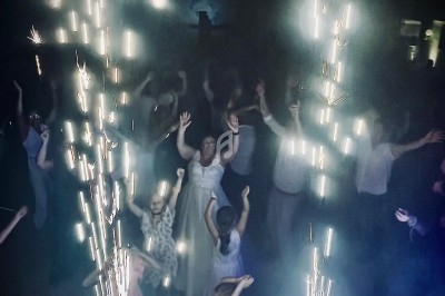 Des personnes dansent dans une ambiance festive avec des étincelles lumineuses en premier plan.