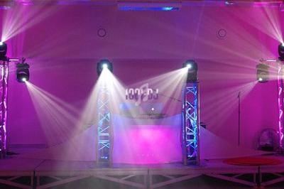 Installation de scène avec éclairage coloré, projecteurs et une table de mixage au centre.