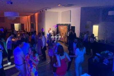 Personnes dansant et discutant dans une salle éclairée par des lumières colorées lors d’un événement festif en intérieur.