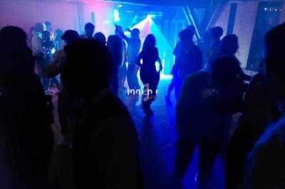 Personnes dansant dans une salle sombre éclairée par des lumières colorées et des effets lumineux.