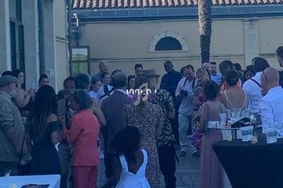Groupe de personnes rassemblées sur une terrasse en bois lors d'un événement en plein air, avec une table dressée au premier…