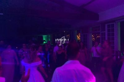 Des personnes dansent dans une salle faiblement éclairée avec des lumières colorées, lors d'une fête ou d'un événement.