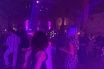 Personnes dansant dans une ambiance festive avec éclairages colorés dans une salle sombre.