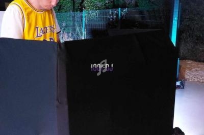 Un DJ portant un casque et un maillot jaune mixe en extérieur, de nuit, devant un équipement audio.