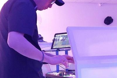 Un DJ mixant de la musique sur une table de mixage dans une salle éclairée de lumières violettes.
