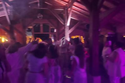 Groupe de personnes dansant dans une salle en bois avec éclairage tamisé et ambiance festive.