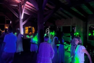 Des personnes dansent dans une salle en bois faiblement éclairée, avec des lumières colorées créant une ambiance festive.