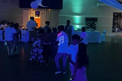 Des personnes dansent dans une salle faiblement éclairée avec des décorations suspendues et des lumières colorées.