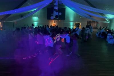 Groupe de personnes dansant en ligne sous des lumières colorées dans une salle décorée pour un événement festif.
