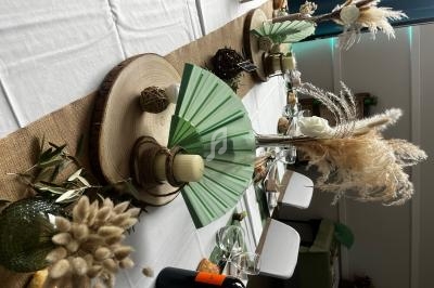 Table décorée avec des éléments naturels, comme des fleurs séchées, des rondins de bois et des éventails verts.