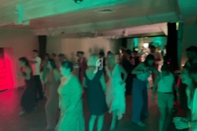 Personnes dansant dans une salle faiblement éclairée avec des lumières colorées vertes et rouges en arrière-plan.