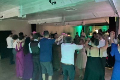 Des personnes dansent en cercle dans une salle éclairée avec des lumières tamisées et une ambiance festive.