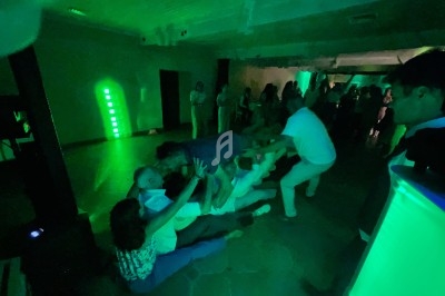 Des personnes participent à une activité collective dans une salle sombre éclairée par des lumières vertes.
