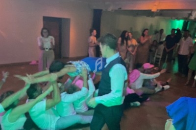 Des personnes participent à une activité festive en intérieur, une femme est portée au-dessus d'un groupe allongé au sol.