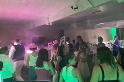 Des personnes dansent dans une salle éclairée par des lumières colorées, ambiance festive et décontractée.