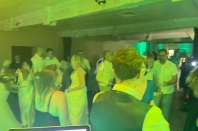 Personnes dansant dans une salle faiblement éclairée avec des lumières vertes, vue depuis une table de mixage.