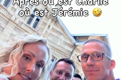 Quatre personnes posent devant un bâtiment en pierre avec une horloge, souriant et regardant l'objectif.