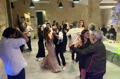 Personnes dansant et discutant dans une salle en pierre éclairée, décorée pour une fête ou un événement festif.