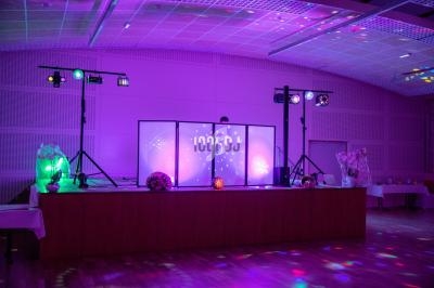 Scène décorée avec des lumières colorées et un écran lumineux dans une salle de réception.