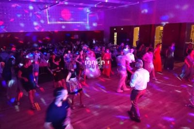 Personnes dansant dans une salle éclairée par des lumières colorées, ambiance festive et conviviale.