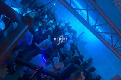 Personnes dansant dans une salle éclairée par des lumières bleues, ambiance festive et animée.