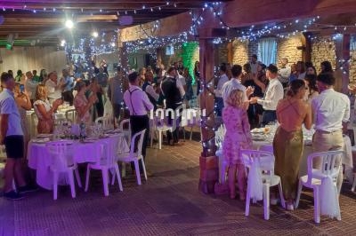 Salle en pierre illuminée avec des guirlandes, remplie d'invités debout et assis lors d'un événement festif.