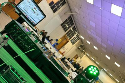 Salle décorée avec des lumières violettes, un arbre artificiel blanc et un mur floral, avec deux personnes présentes.