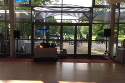 Salle décorée avec des lumières violettes, un arbre artificiel blanc et un mur floral, avec deux personnes présentes.
