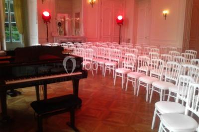 Façade d'un château illuminé la nuit avec une fontaine ornée de statues au premier plan.